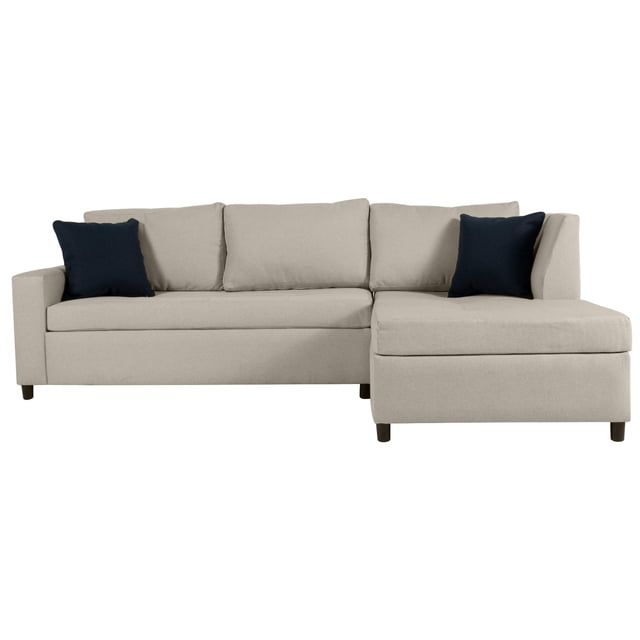 sala modular derecha easy living tarento beige, vista frontal 3/4 con chaise a la derecha; sofá modular beige de silueta recta con estructura de madera de pino, tapizado en polister y cojines de asiento y respaldo con relleno de espuma de confort suave; incluye cuatro respaldos sueltos, dos cojines decorativos oscuros y patas cortas en tono madera sobre fondo blanco; apta para espacios pequeños y decoración moderna.