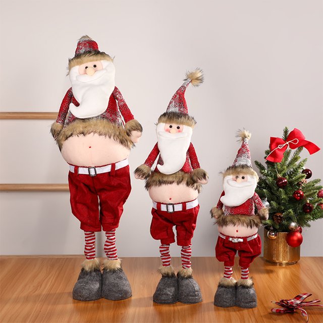 fiudx muñeco de ciervo navideño con patas retráctiles, poliéster multicolor, altura ajustable y extensión de patas de 24 x 100 cm, vista frontal de tres figuras decorativas con gorro puntiagudo, barba blanca, cinturón plateado, pantalones rojos, patas rayadas y bases de fieltro sobre piso de madera y fondo interior neutro, ideal como adorno navideño para fiestas y a menudo usado como pieza decorativa de mesa o entrada.