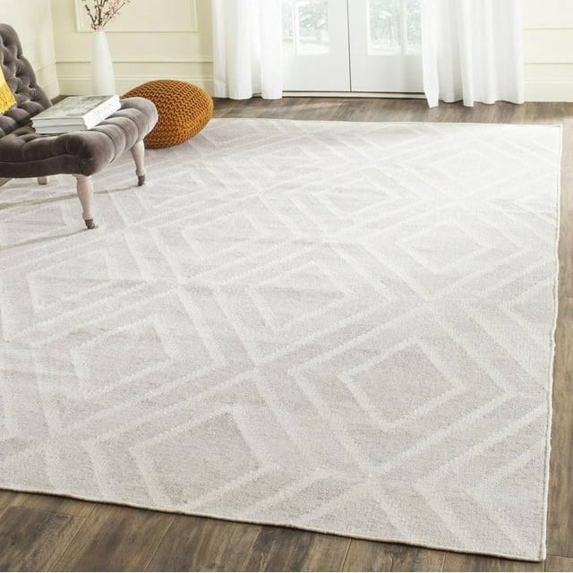 Safavieh Kilim Lorcan light beige area rug featuring subtle geometric diamond patterns on hardwood floor near tufted chair and window.
