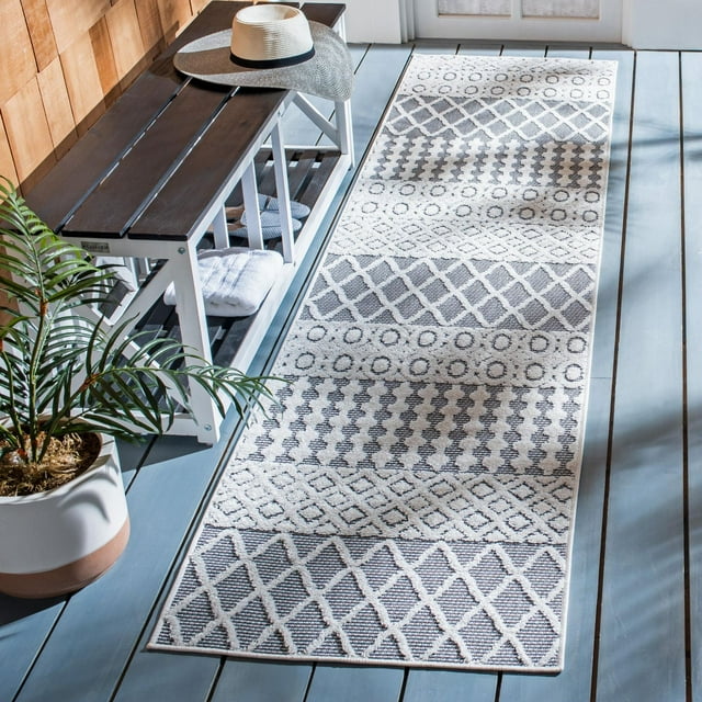 SAFAVIEH Cabana Elouise geometric indoor/outdoor area rug in neutral tones displayed on blue wooden flooring next to a white bench with accessories.