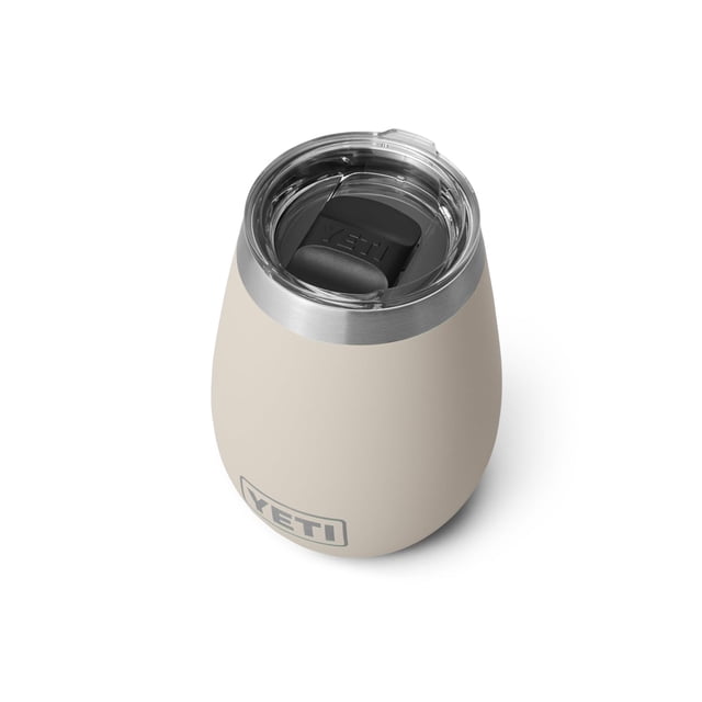 vaso de vino yeti rambler, 300 ml, con aislamiento al vacío, acero inoxidable Beige; vista cenital 3/4 de un vaso Rambler de 10 oz con cuerpo redondeado y revestimiento Duracoat beige, borde de acero inoxidable cepillado y tapa MagSlider transparente con deslizador negro marcado YETI. Diseñado para mantener bebidas frías o calientes en exteriores; también se usa como termo de hidratación portátil para viajes.