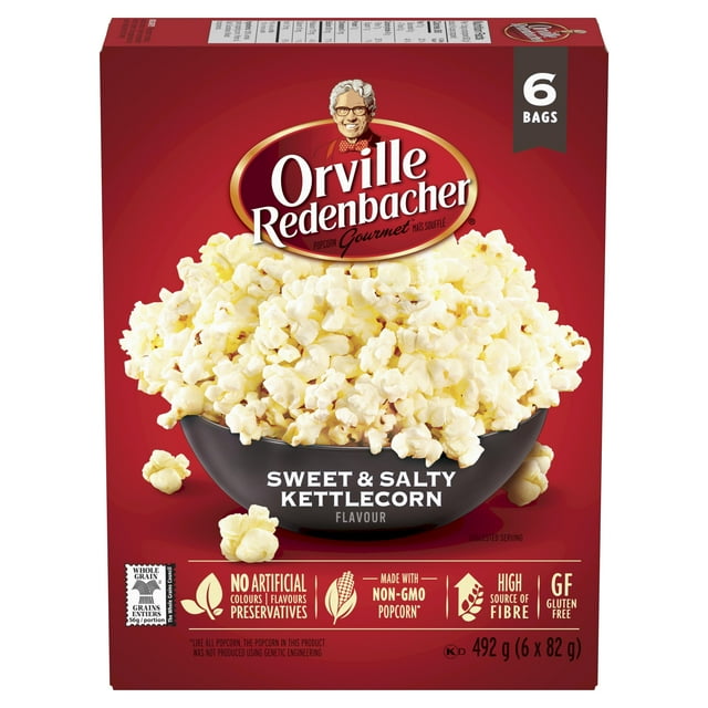 Orville Redenbacher Sweet & Salty Kettlecorn Microwave Popcorn 6 bags (492 g) box showing a black bowl overflowing with fluffy kettlecorn on a red background, featuring no artificial colours, flavours, preservatives, non-GMO popcorn, high fibre, and gluten-free attributes, suitable for sharing during family movie nights.