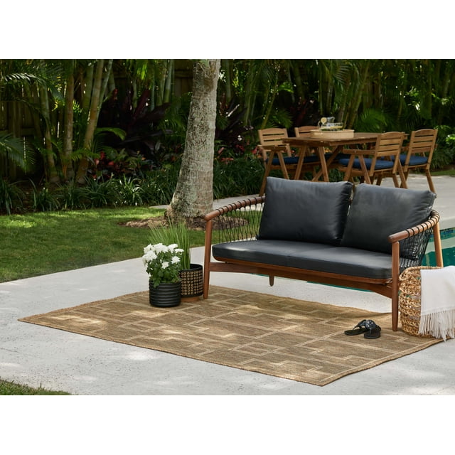 ECARPET Dune transitional area rug featuring a subtle geometric design, displayed outdoors beneath a wooden bench with black cushions by the pool.
