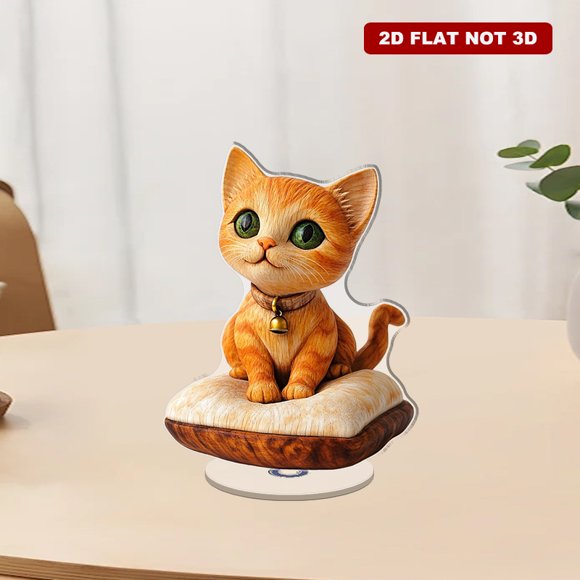 A rotating acrylic ornament featuring a handcrafted orange tabby kitten sculpture with big green eyes on a soft cushion, capturing its charming details and smooth finish