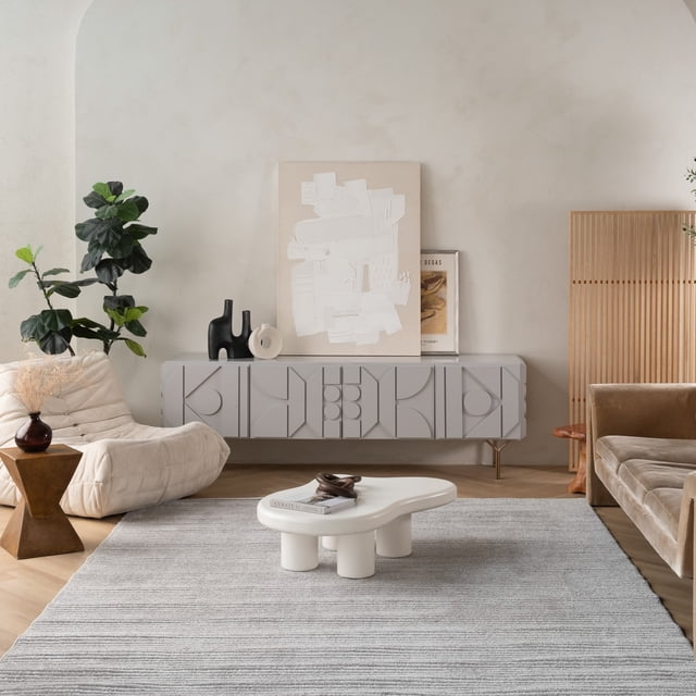 Cream beige modern indoor outdoor area rug in a stylish living room featuring a white abstract coffee table, textured gray sideboard, and neutral seating.
