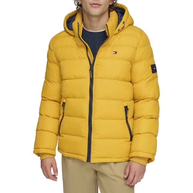 chaqueta tommy hilfiger classic con capucha acolchada para hombre, color amarillo — vista frontal centrada de chamarra acolchada amarilla con cierre frontal negro, capucha forrada, costuras horizontales tipo guata, dos bolsillos laterales con cremalleras y bandera Tommy Hilfiger bordada en el pecho izquierdo; parche de marca en la manga y puños de punto acanalado visibles.