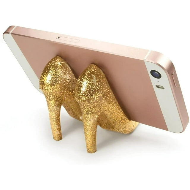 base para celular en forma de zapatillas glitter tigsa dorado, soporte de silicón para teléfonos tipo iPhone con figura de par de tacones altos y acabado glitter; vista 3/4 sosteniendo un teléfono en horizontal, dimensiones aprox. 4 x 7 x 14 cm. A menudo se usa también como soporte decorativo para tarjetas o notas pequeñas.