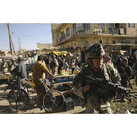 US Army Specialist moves through an open-air market during a foot patrol in Iraq Stretched Canvas - Stocktrek Images (34 x