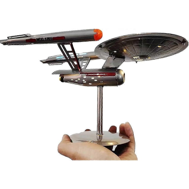 u.s.s. enterprise star trek model ncc-1701 replica,stainless steel spaceship model ornaments for home decoration and collection réplica de la Enterprise NCC-1701 en acero inoxidable con luces LED, vista 3/4 frontal sostenida en una mano; disco principal con ranuras, dos pilones hacia módulos propulsores cilíndricos con ventanas pintadas y puntas rojas/anaranjadas, soporte metálico ajustable, dimensiones 30×15×20 cm, ligera y apta como adorno o pieza de colección para fans.
