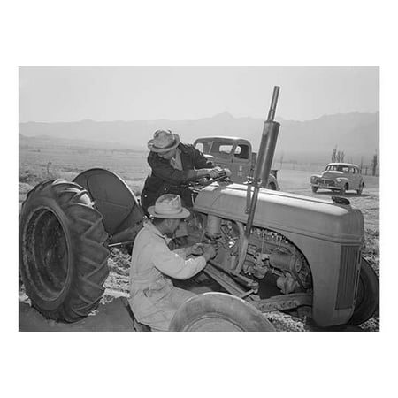Mechanic repairs tractor engine while driver looks on pick-up truck and automobile in the background  Ansel Easton Adams was an American photographer best known for his black-and-white photographs
