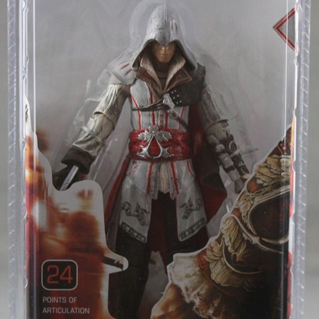 neca assassin's creed 2 doll model altaïr white killer ezio revelations figura móvil de 7 pulgadas Figura de acción NECA Altaïr en blister, vista frontal, 7 pulgadas; traje blanco con capucha, cinturón rojo ornamentado, guantelete oculto y articulaciones visibles para posado; embalaje con ilustración y sello "24 points of articulation". A menudo se usa también como pieza de colección en vitrinas de fandom.