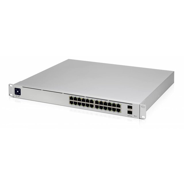 switch ubiquiti usw-pro-24 de capa 3 sin puertos poe 24 montable en rack, vista frontal 3/4 con 24 puertos GbE RJ45 en dos filas, chasis metálico plateado, puerto SFP para enlaces de fibra óptica en el extremo derecho y entrada de alimentación integrada a la izquierda; diseñado para conmutación de capa 3 en redes empresariales y a menudo usado también para pruebas y enlaces internos en racks de laboratorio de redes.