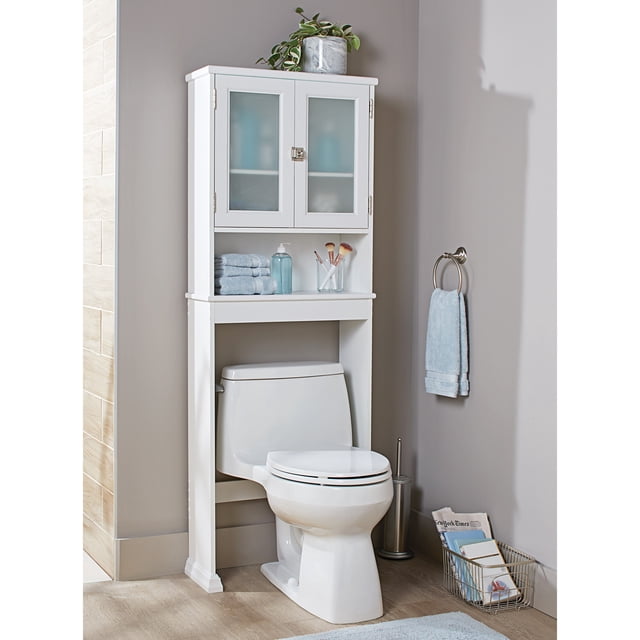 Better Homes & Gardens white over-the-toilet bathroom space saver cabinet with frosted glass doors, shelves holding folded towels and toiletries in a modern bathroom