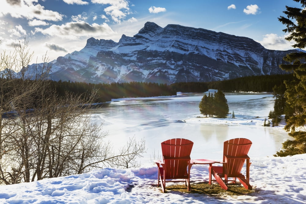 Two red chairs on snow covered ridge overlooking frozen lake with snow covered mountain in the background with blue sky and clouds Banff Alberta Canada Canvas Art - Michael Interisano Design Pics (38