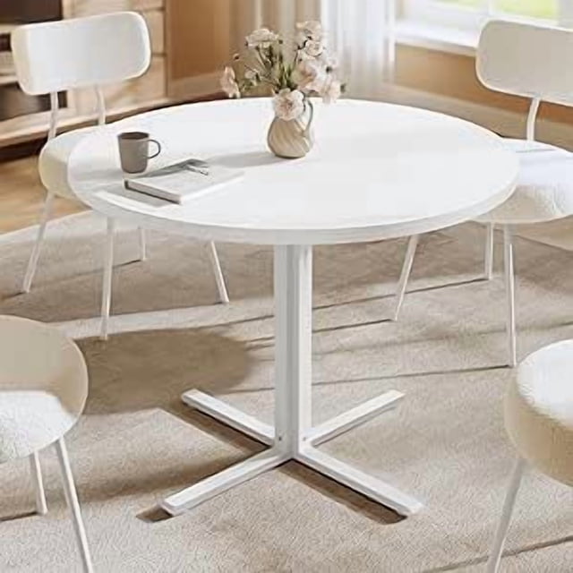 VASAGLE Dining Table, a small round kitchen table with a 31.5-inch diameter and 29.4-inch height, designed for 2-4 people. The table features a snow white finish, a durable particleboard tabletop with a water-resistant and heat-resistant veneered surface, and a sturdy C-shaped steel frame with adjustable feet for stability. Ideal for dining rooms, living rooms, or farmhouse-style interiors, it combines modern farmhouse charm with functionality. Shown in a bright dining room setting with matching white chairs and a vase centerpiece.