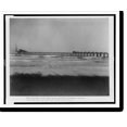 thumbnail image 2 of Historic Framed Print, View near outer end of jetty, showing revolving pile driver swinging about with pile, and train load of rock, one car dumped, 17-7/8" x 21-7/8", 2 of 9