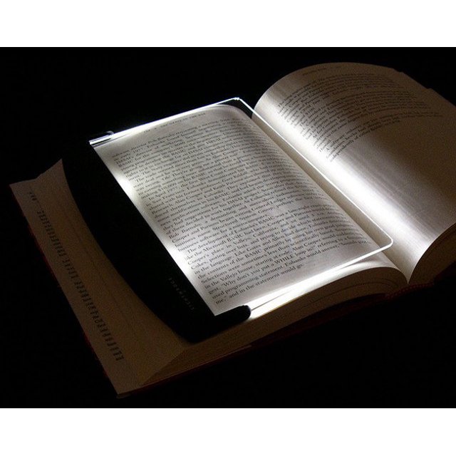 libro ojo de lectura inalámbrico oso de fresa panel led portátil, vista 3/4 de un panel LED blanco y delgado sobre páginas abiertas de un libro, borde iluminado que proyecta una franja de luz concentrada sobre el texto, fondo oscuro tipo dormitorio; tamaño aprox. 170 x 140 mm, funciona con 3 pilas AAA (no incluidas), apto para lectura nocturna y a menudo usado como marcador portátil.