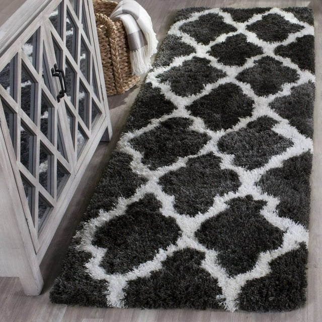 Safavieh Barcelona Anabelle dark gray and white geometric shag area rug displayed on a light wood floor beside a glass-front cabinet with black handles and woven basket