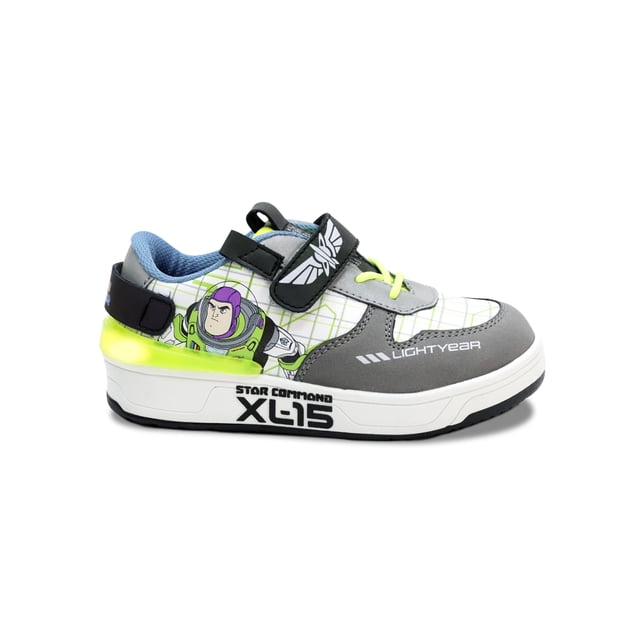 tenis para niño Disney Pixar Toy Story, tenis casuales blancos con diseño de Buzz Lightyear, vista lateral derecha; velcro en el empeine, agujetas elásticas amarillas, detalles gris y verde neón, suela blanca con texto 'XL-15' y luces LED en el talón, plantilla acolchada visible. Su tamaño compacto los hace adecuados para uso diario y viajes cortos.