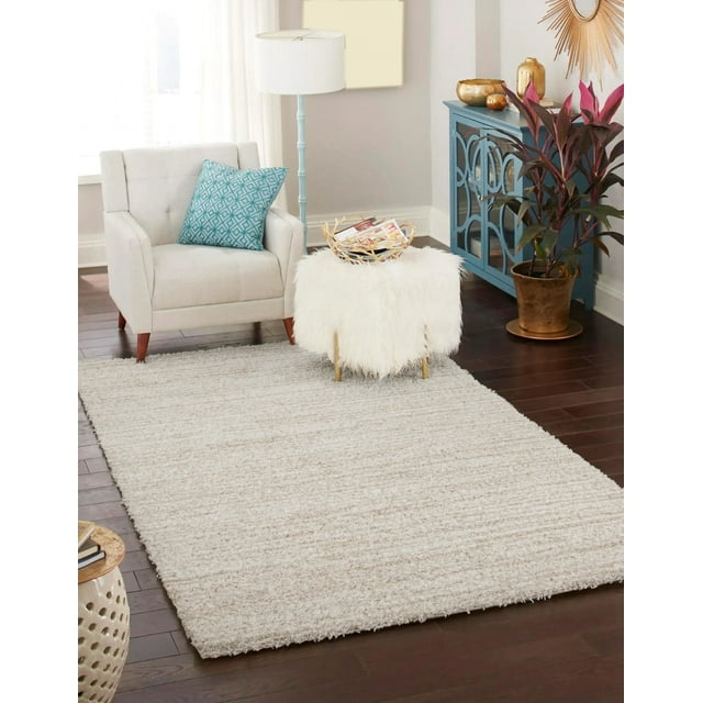 ECARPET Yeti plush beige shag area rug on dark hardwood floor in contemporary living room setting with light armchair and decorative furniture.