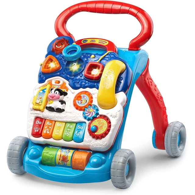 vtech sit-to-stand learning walker andadera y centro de actividades amarillo, ayuda al desarrollo de equilibrio; vista 3/4 frontal con asa roja, chasis azul y bandeja amarilla extraíble sobre cuatro ruedas grises. Panel desmontable con cinco teclas de piano Do-Re-Mi-Fa-So, engranajes giratorios, tres rodillos coloridos, clasificadores de formas iluminadas, tres botones iluminados y teléfono de juguete; estimula primeras palabras y entrenamiento auditivo para bebés de 9 meses a 3 años. A menudo usado también como panel de juego independiente en el suelo.