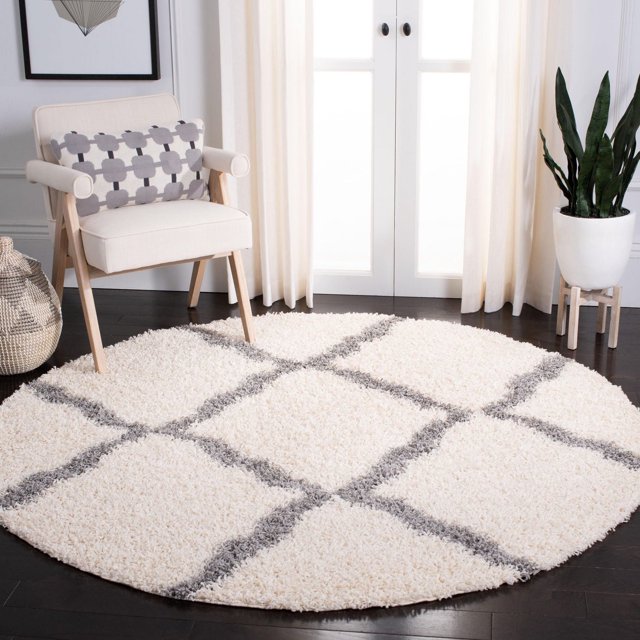 Round Safavieh Dallas Logan Geometric Shag Area Rug in white with gray grid lines, placed on dark hardwood floor under a beige armchair and near potted plant.