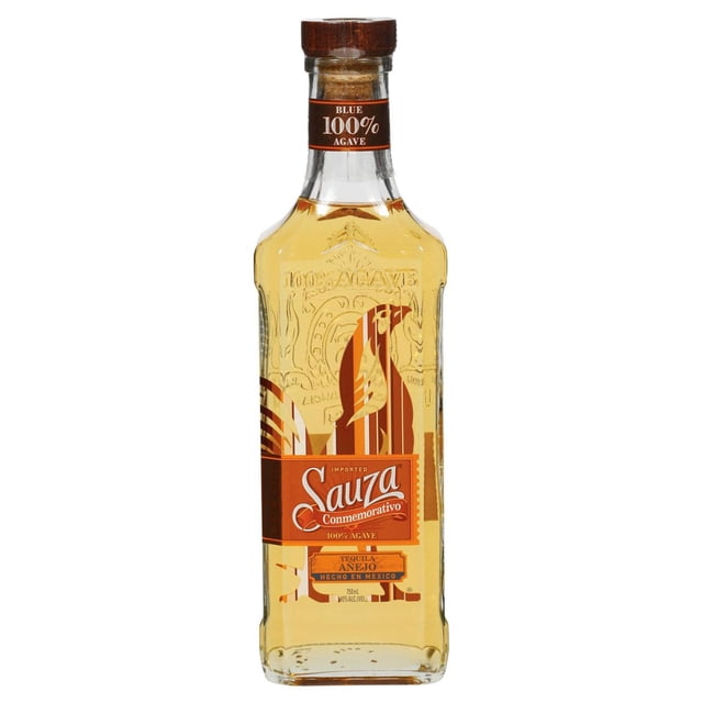 tequila sauza conmemorativo añejo 750 ml botella rectangular de vidrio ámbar con etiqueta naranja y logo Sauza, relieve '100% agave' en el cuello y tapa tipo madera, vista frontal sobre fondo blanco; suele usarse también como pieza de barra para cenas y eventos navideños.
