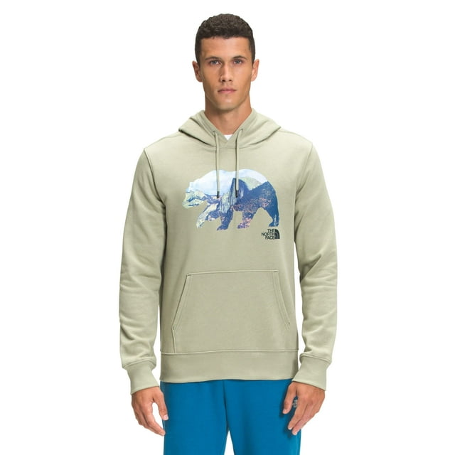 sudadera con capucha the north face tnf bear para hombre, color verde té, talla xl vista frontal centrada con capucha con cordón, ajuste estándar, bolsillo canguro y dobladillos acanalados; gran gráfico de oso con paisaje e insignia The North Face en el pecho, tejido mezcla algodón-poliéster de peso medio con textura suave, modelo sobre fondo neutro. Su tamaño la hace adecuada para senderismo ligero o uso diario.