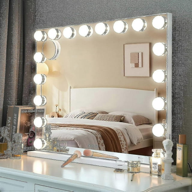 espejo de maquillaje led estilo hollywood con luz led regulable (solo bombilla) dd.14 lights espejo rectangular frontal con 14 bombillas redondas LED montadas alrededor del marco, luz en tono cálido mostrada, cable extra oculto en la base y cinta 3M doble cara en el borde, sobre tocador con brochas y frascos de cosmético; incluye 3 temperaturas de color y 10 niveles de brillo, suele usarse también para fotografía y streaming.