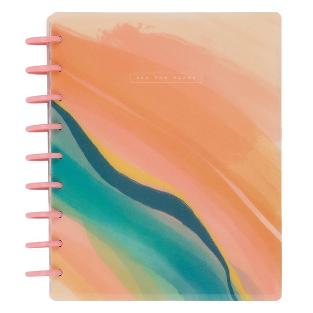 planner the happy planner, sostenible, encuadernado en disco, 12 meses — portada en acuarela con pinceladas melocotón y coral y franjas verdes y turquesa; discos plásticos rosas en el lomo y cubierta laminada resistente; diseño del tablero con espacio para listas y cajas diarias, adecuado para planear meses 2025–2026.