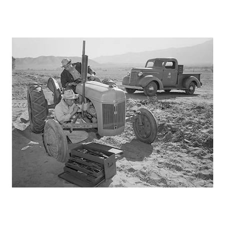 Mechanic repairs tractor engine while driver looks on tool box in the foreground pick-up truck in the background  Ansel Easton Adams was an American photographer best known for his black-and-white