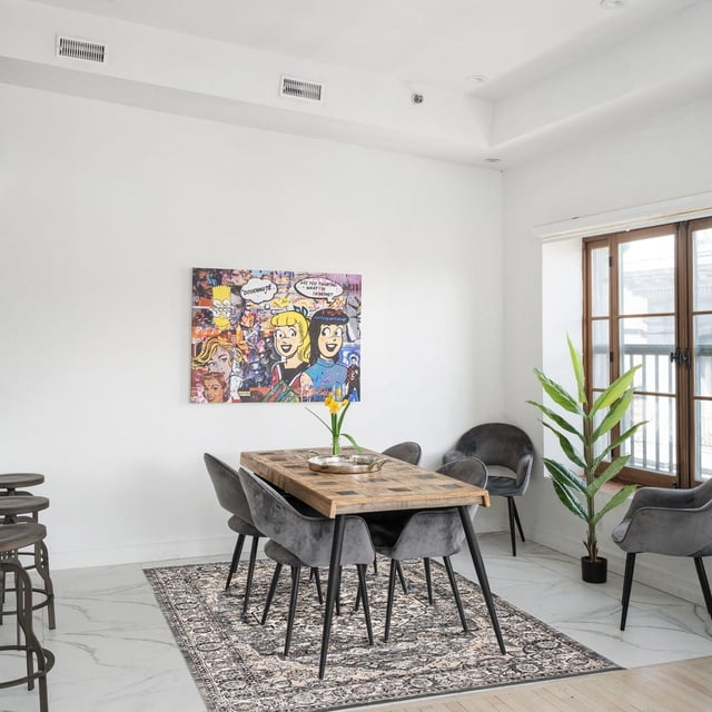 ECARPET Vintage Oriental area rug from the Oregon Tabriz Collection placed under a wooden dining table surrounded by six gray upholstered chairs in a modern, bright living space with white walls and natural light.