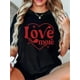 thumbnail image 1 of Camiseta gráfica elegante "Love More" para San Valentín para mujer. Camiseta negra informal con diseño de corazón rojo, manga corta y cuello redondo. Lavable a máquina. Ideal para primavera y verano., 1 of 6