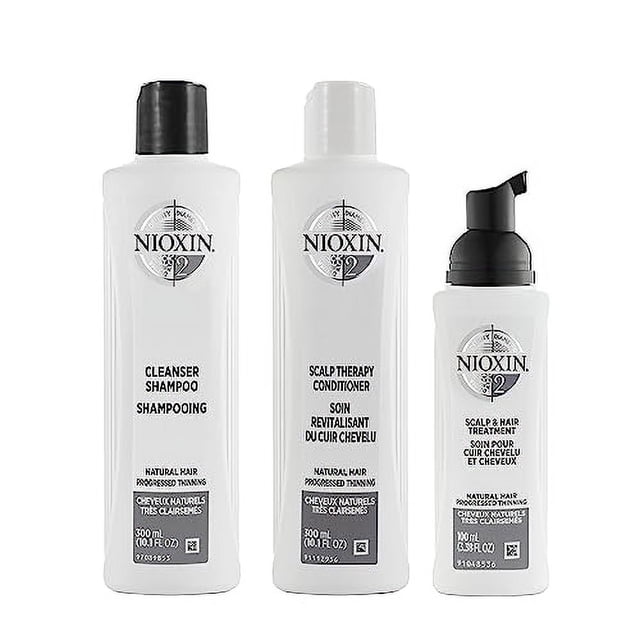 kit del sistema nioxin 2, tratamiento fortalecedor y espesante del cabello — vista frontal centrada de tres botellas blancas: limpiador champú (300 ml, tapa negra), acondicionador scalp therapy (300 ml, tapa blanca) y tratamiento scalp & hair con dosificador negro; etiquetas con logotipo Nioxin y texto en varios idiomas sobre fondo blanco; formulado para cabello natural con adelgazamiento progresado y uso en un régimen volumizante de tres pasos; también suele usarse para refrescar el cuero cabelludo antes de peinados de volumen.
