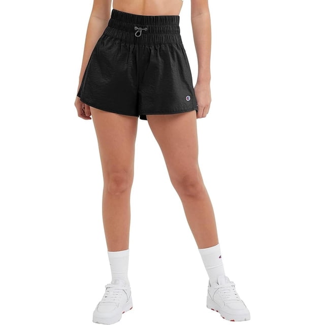 short champion woven 2.5 para mujer. m9270-586644-001 negro s pantalones cortos negros de mezcla ligera con pretina ancha fruncida y cordón ajustable; vista frontal centrada hasta la mitad del muslo, logo Champion bordado en la pernera derecha; modelo con calcetas y tenis blancos. También suelen usarse para entrenamiento ligero o como short de descanso.
