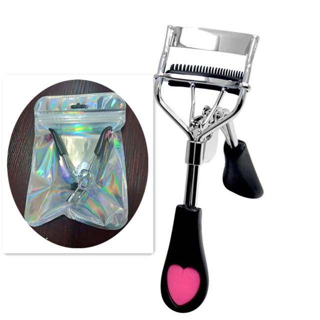 rizador de pestañas tunc herramienta de maquillaje profesional negro, vista 3/4 frontal con arco de acero inoxidable y resorte visible; almohadilla de silicona elástica y cabezal con cepillo integrado para rizar sin pellizcar, mango negro con detalle rosa en forma de corazón, incluye empaque holográfico; también suele usarse para preparar pestañas antes de aplicar extensiones o maquillaje.