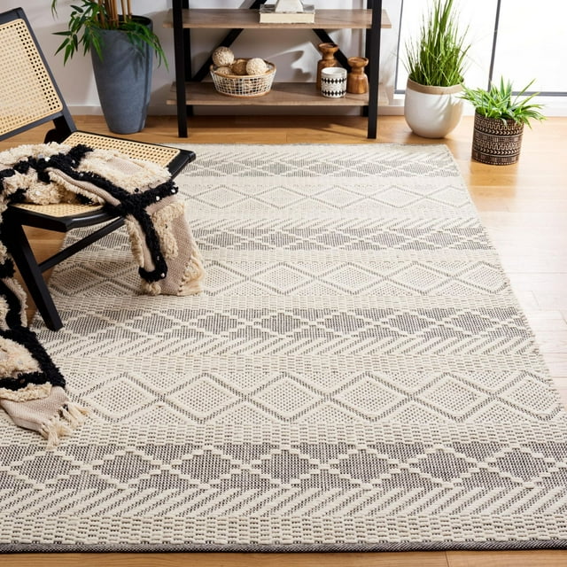 SAFAVIEH Natura Aaron Bohemian area rug featuring beige and gray geometric patterns on hardwood floor, styled with modern decor including woven chair, throw blanket, potted plants, and shelving unit.