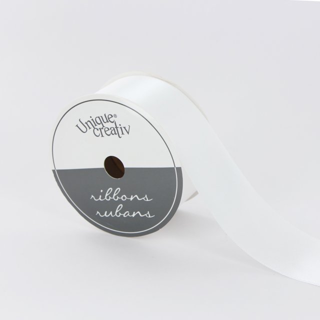 UNIQUE CREATIV Ribbon, single face satin in white, 38mm by 3.65m (1½" x 4 yds), 100% polyester, shown partially unrolled from a spool with a white and gray label featuring the brand and 'ribbons rubans' text, suitable for crafts, sewing, floral arrangements, and gift wrapping.