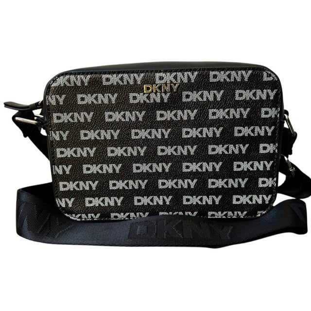 bolsa crossbody dkny tutu camera black bolso tipo camera negro con monograma DKNY repetido, logo metálico dorado en el frente, cierre superior con cremallera y correa ancha ajustable con texto DKNY en tejido; vista frontal centrada sobre fondo neutro. Su tamaño compacto la hace adecuada para uso diario y a menudo se usa para llevar esenciales como teléfono y cartera de forma organizada.
