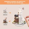 thumbnail image 3 of Rotating acrylic display showcasing a realistic bunny in a flowery Easter basket holding a camera on a cobblestone platform with intricate details, 3 of 8