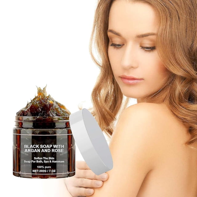 jabón negro beldi, jabón negro con argán y rosa, jabón exfoliante marruecos — tarro frontal con gel negro espeso en envase oscuro y tapa plateada al lado, etiqueta en inglés visible; a la derecha hombro y espalda de mujer con piel clara sobre fondo blanco que sugiere uso corporal y exfoliante corporal; indicado para limpieza e hidratación según la etiqueta. Suitable for uso facial y corporal diario.