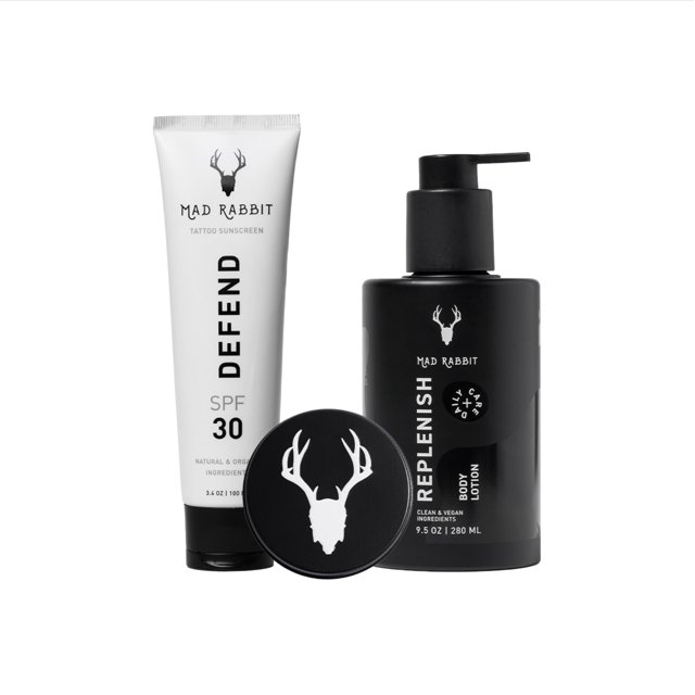 kit de cuidado de tatuajes mad rabbit enhance balm lotion & protector solar — tres envases frontales: tubo blanco de protector solar mineral SPF 30 marcado "DEFEND", tarro negro con logo de cráneo de ciervo y botella negra con dosificador etiquetada "REPLENISH"; composición sobre fondo blanco, indicado para hidratación diaria y protección solar de piel tatuada.