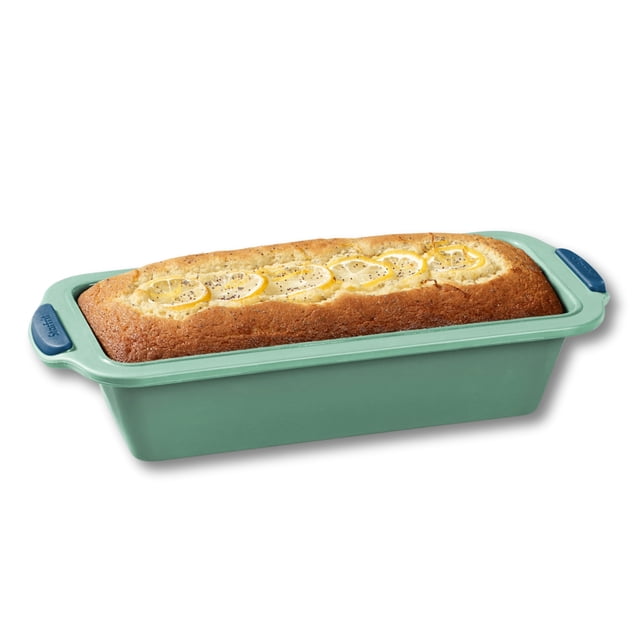 Starfrit Silicone Baking Pan - Loaf Pan with Integrated Metal Frame in green, 9.5” x 4” (24 cm x 10 cm), holding a baked lemon loaf topped with lemon slices, featuring ergonomic blue grip handles and a flexible silicone body with a sturdy metal frame, suitable for oven, microwave, and air fryer use.