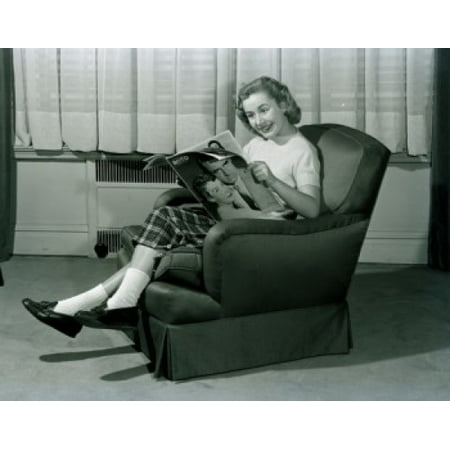 - young woman sitting in armchair reading magazine Poster Print
