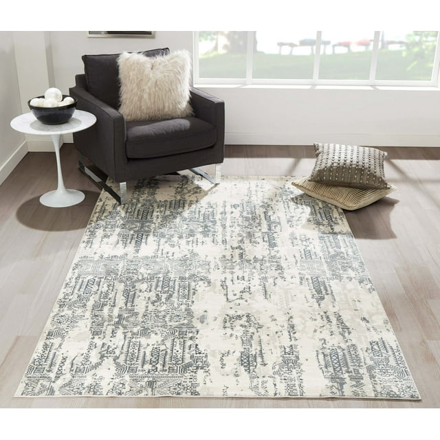 ECARPET Claudia traditional area rug with distressed gray and beige geometric patterns under a dark armchair and decorative pillows on light wood flooring.