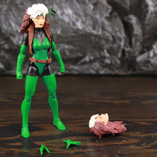 marvel legends x-men rogue 6 "figura de acción retro refundido chaleco para la cabeza cinturón outback exclusivo x men comics juguetes modelo de muñeca" C Two Heads Ver. — Vista frontal de figura Rogue escala 1/12 en PVC con traje verde y negro, chaleco y cinturón marrón; accesorios visibles: cabeza intercambiable con mechón blanco y par de manos adicionales sobre la base; fondo de estudio gris oscuro. Recomendada 18+. A menudo usada para dioramas y exhibiciones de cómic.