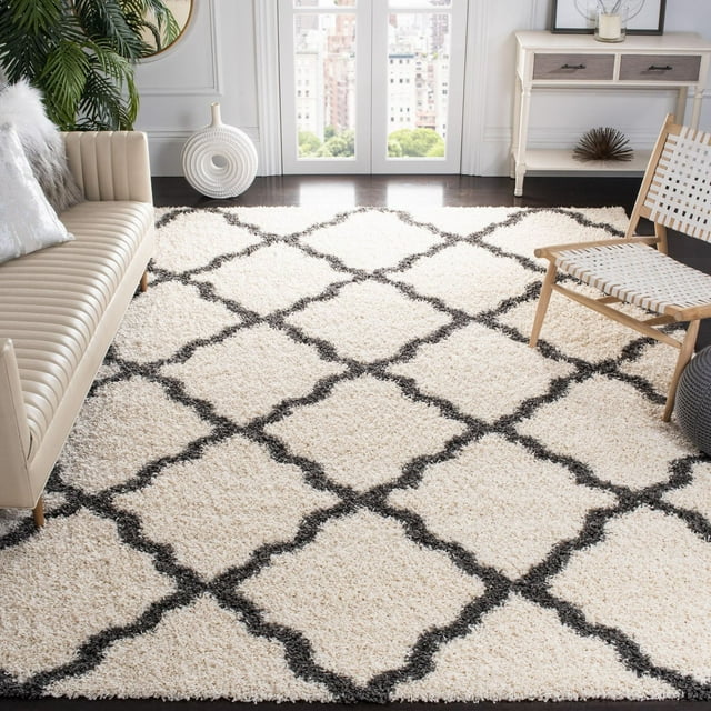 Safavieh Dallas Logan cream shag area rug featuring a black geometric diamond pattern, styled in a contemporary living room with beige sofa and wooden chair.