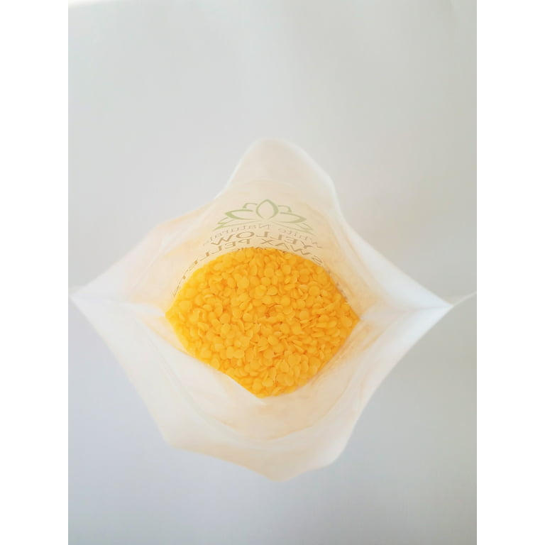 yellow and white cosmetic beeswax pellets in white ceramic bowl for  homemade natural beauty and D.I.Y. project. Stock Photo