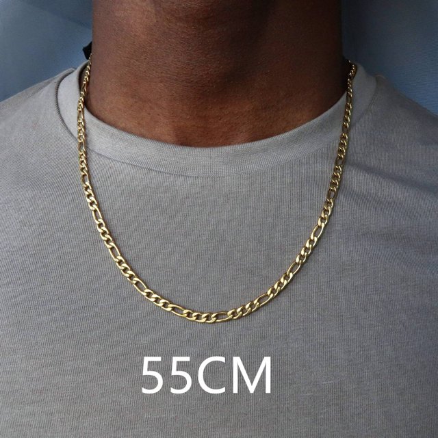 collar de cadena figaro de acero inoxidable para hombres, collar largo de color dorado, 3mm 55 cm: vista frontal centrada de un collar Figaro dorado sobre el pecho de un modelo; eslabones alternos planos y ovalados en acero inoxidable con acabado brillante, caída hasta el esternón sobre camiseta gris; estilo de moda vintage ideal para fiesta y regalo, también apto para uso diario.