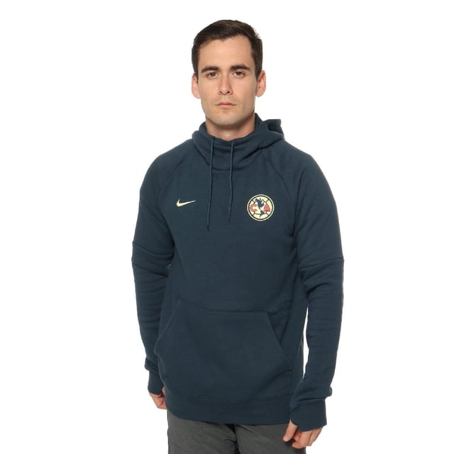 sudadera nike hombre club américa gfa po at4415454 azul m 6at4415454 Sudadera azul para hombre con capucha y cordón, vista frontal centrada que muestra silueta regular y cuello alto; bolsillo tipo canguro, mangas largas con aberturas para pulgares, escudo del Club América bordado en el pecho izquierdo y logo Nike bordado en el pecho derecho; fondo neutro de estudio. Suele usarse también para viajes cortos por su tamaño compacto.